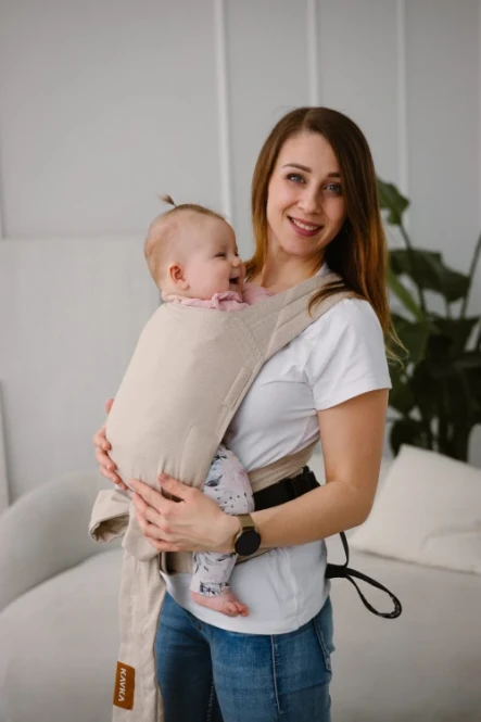 Modelka-nosi-dziecko-w-ergonomicznym-nosidle-KAVKA-handy-vanilla-twill----bezowe-nosidlo-z-bialym--wzorem-w-drobna-jodelke--a-beige-baby-carrier-with-white-twill--pattern.webp